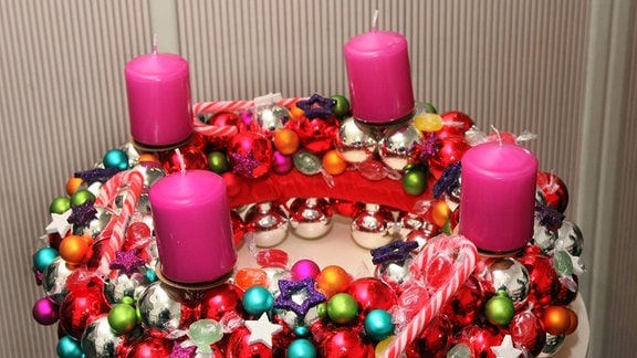 Adventskranz mit bunten Kugeln und rosa Kerzen