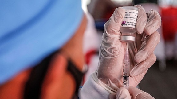 Ein Impfarzt zieht eine Spritze mit Astrazeneca-Impfstoff auf.