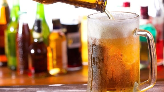 Eine Flasche Bier wird in einer Bar in ein Glas eingeschenkt.