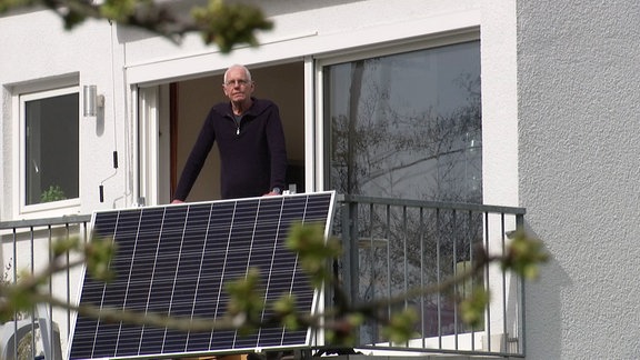 Ein Mann mit Solarzellen auf einem Balkon