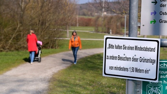 Schild mit Aufschrift 'Bitte halten Sie einen Mindestabstand zu anderen Besuchern dieser Grünanlage von mindestens 1,50 Metern ein'