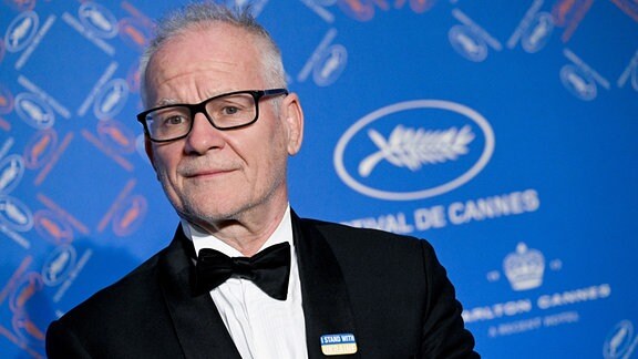 Porträt eines Mannes im Anzug. Im Hintergrund Schriftzug "Festival de Cannes"