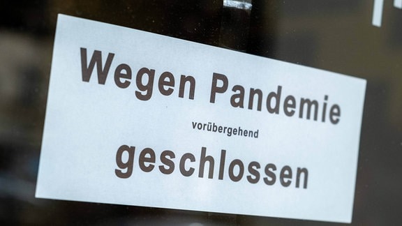 Wegen Pandemie vorübergehend geschlossen - Schild an der Ladentür