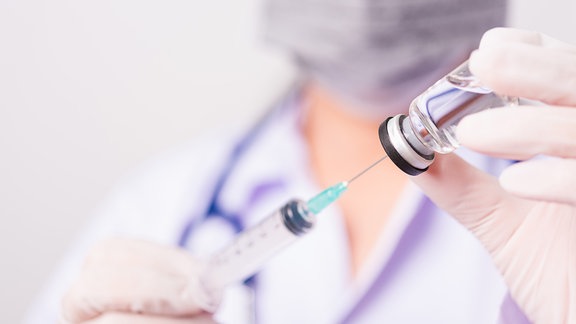 Ärztin hält Spritze und Impfstoff-Ampulle