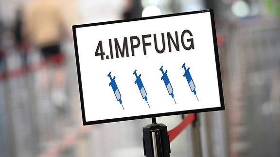 Fotomontage: Aufschrift 4. Impfung und vier Spritzen auf einem Schild