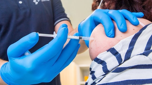 Ein Hausarzt impft einen Patienten mit einer Schutzimpfung gegen das Coronavirus. 