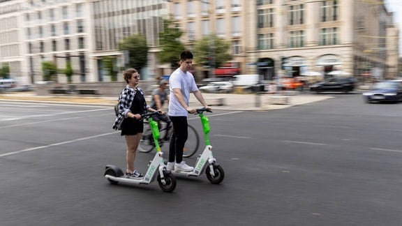 Eine Frau und ein Mann fahren auf E-Scooter 