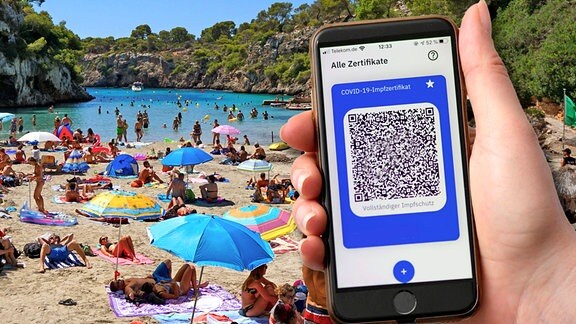 Bildmontage Ein Impfpass in digitaler Form der CovPass-App auf dem Smartphone, gehalten vor einer Strandszene