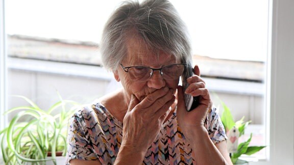 Seniorin, entsetzt am Telefonhörer