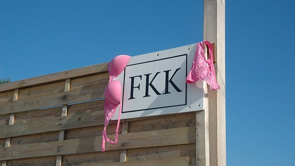 Schild mit der Aufschrift FKK, daneben hängt Unterwäsche