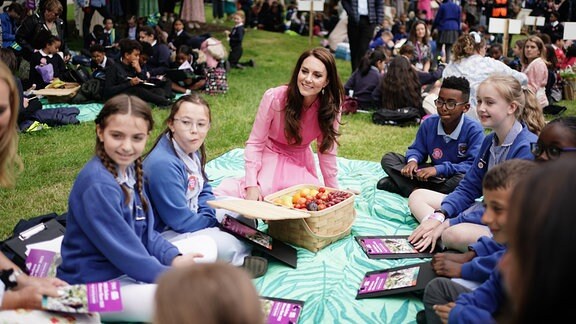 Prinzessin Kate sitzt mit Kindern bei einem Picknick.