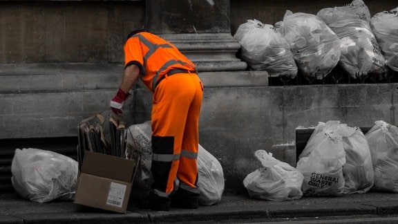 Mann sammelt Müll auf Straße