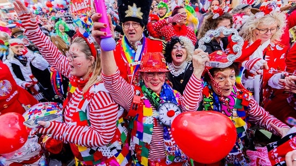 Verkleidete Menschen mit rot-weiß gestreiften Oberteilen feiern Karneval.