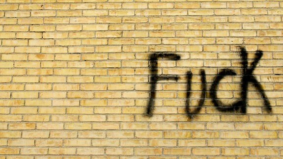 Eine beschmierte Ziegelwand mit dem Wort "Fuck"