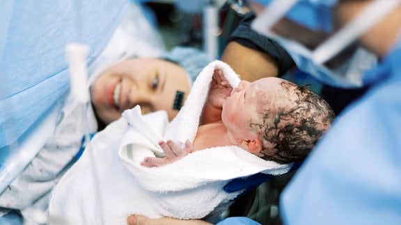 Neugeborenes neben seiner Mutter im OP