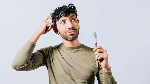 Nachdenklicher Mann hält Zahnbürste 
