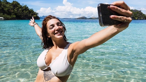 Frau macht Selfie mit Smartphone im Meer
