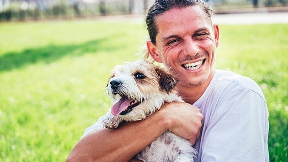 Lachender Mann hält Hund im Arm