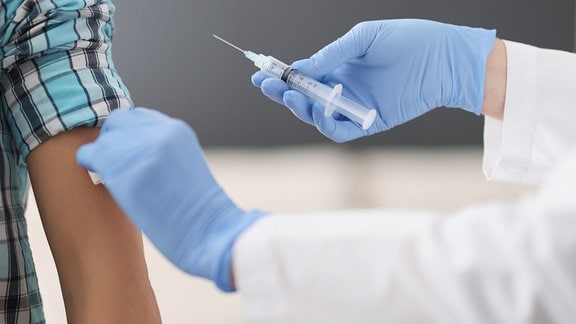Eine Person wird am Arm für eine Impfung desinfiziert.