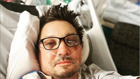 Jeremy Renner in einem Krankenhausbett mit Wunde im Gesicht