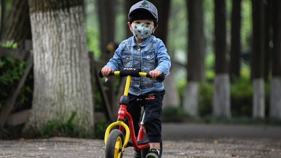 Ein Kind mit Mundschutz und Roller im Zoo von Wuhan