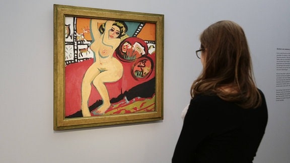Eine junge Frau betrachtet ein expressionistisches Gemälde.