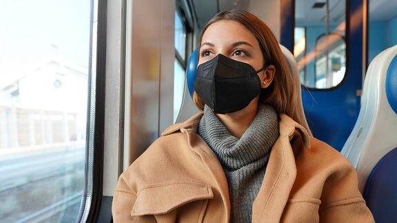Frau trägt medizinische Maske im Zug