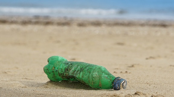 Eine Plastikflasche leigt am Strand.