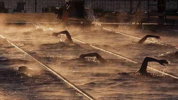Schwimmer schwimmen durch Dampf eines beiheizten Beckens