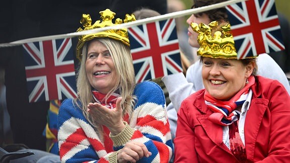 Zwei Frauen sind in den Farben der englischen Flagge gekleidet und tragen Kronen.