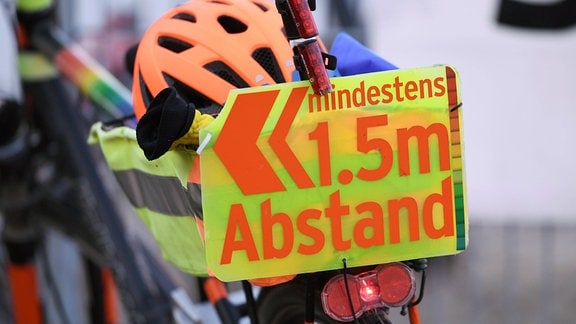 Ein Schild an einem Fahrrad >>mindestens 1,5 m Abstand<<