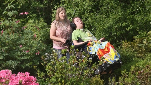 Judy Machiné geht 2012 im Garten des Kinderhospiz Löwenherz mit ihrem im Rollstuhl sitzenden todkranken Sohn Daniel spazieren.