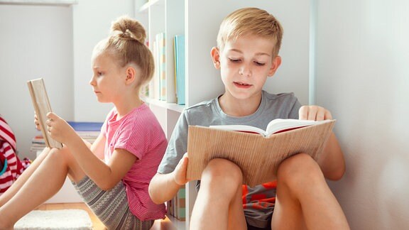 Ein Mädchen und ein Junge lesen in Büchern