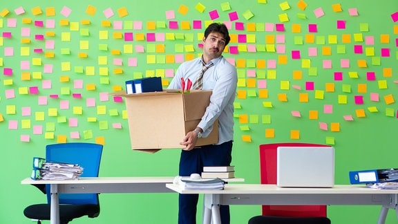 Symbolfoto Kündigung - Ein Büroarbeiter hält eine Kiste mit seinen persönlichen Sachen