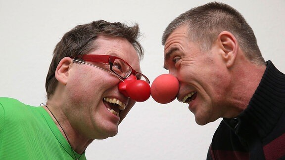 Zwei Männer mit Clownsnasen lachen