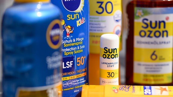 Verschiedene Produkte für den Sonnenschutz stehen auf einem Balkon auf einem Tisch.