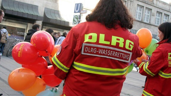 Mitarbeiterinnen der Deutschen Lebensrettungsgesellschaft DLRG stehen zur Werbung von Spenden in einer Fußgängerzone