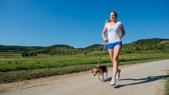 Eine Frau joggt mit ihrem Hund