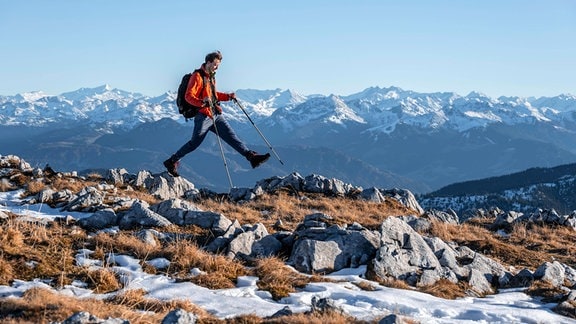 Bergsteiger macht einen großen Schritt, vor Bergpanorama