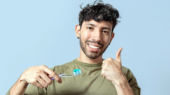 Junger Mann hebt den Daumen fürs Zähneputzen