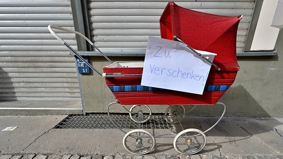 Roter Kinderwagen mit handgeschriebenem Zettel: "zu verschenken"
