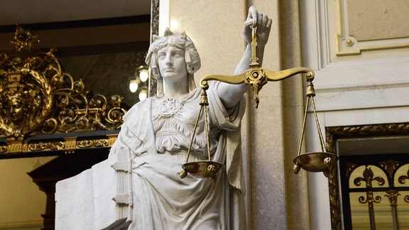 Statue der Gerechtigkeit mit Gesetzestext und Waage