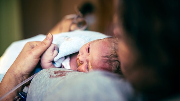 Frau hält ihr Neugeborenes nach der Geburt im Krankenhaus.