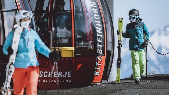 Skifahrer mit FFP 2 Masken verlassen die Gondel