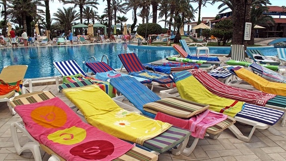 Sonnenliegen belegt mit Handtüchern an einem Pool