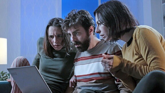Drei Leute schauen entsetzt auf einen Laptopbildschirm