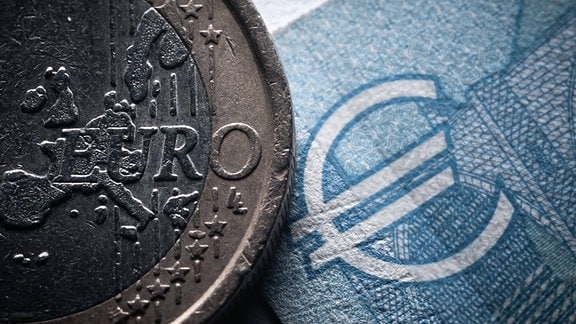 Der Schriftzug Euro ist auf einer 1-Euro Münze neben einem 20-Euro-Schein sehen. 
