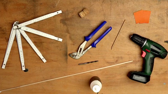 Auf einem Tisch liegt Werkzeug für einen selbstgebastelten Taktstock.