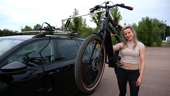 Eine junge Frau, ein E-Bike und ein Pkw