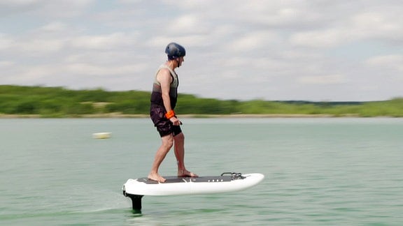 Ein Mann gleitet auf dem Multifunktionsgerät über das Wasser.